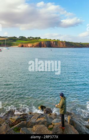 Un pescatore con un bellissimo paesaggio sullo sfondo sulla costa dell'Irlanda Foto Stock