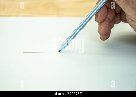 La mano di un uomo che dipinge una linea con una matita di grafite Foto Stock