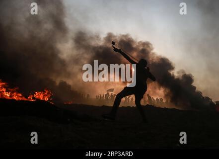 (180928) -- GAZA, 28 settembre 2018 () -- Un manifestante palestinese usa una fionda per lanciare pietre contro le truppe israeliane durante gli scontri sul confine tra Gaza e Israele, a est della città di Gaza, il 28 settembre 2018. Almeno sei palestinesi sono stati uccisi e più di 500 feriti venerdì durante gli scontri settimanali con soldati israeliani di stanza al confine tra la Striscia di Gaza orientale e Israele, hanno detto i medici. (/Stringer) MIDEAST-GAZA-CLASHES Xinhua PUBLICATIONxNOTxINxCHN Foto Stock