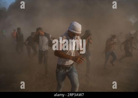 (180928) -- GAZA, 28 settembre 2018 () -- i manifestanti palestinesi corrono per coprire i gas lacrimogeni durante gli scontri con le truppe israeliane sul confine tra Gaza e Israele, a est della città di Gaza, il 28 settembre 2018. Almeno sei palestinesi sono stati uccisi e più di 500 feriti venerdì durante gli scontri settimanali con soldati israeliani di stanza al confine tra la Striscia di Gaza orientale e Israele, hanno detto i medici. (/Stringer) MIDEAST-GAZA-CLASHES Xinhua PUBLICATIONxNOTxINxCHN Foto Stock