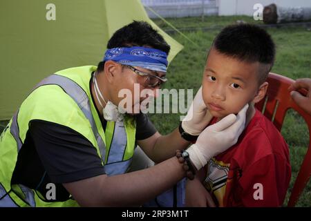 (181010) -- PALU, 10 ottobre 2018 -- il volontario cinese Du Hailang (L) aiuta un ragazzo ferito a Palu, Indonesia, il 9 ottobre 2018. I terremoti devastanti e lo tsunami che ne seguì devastarono la provincia centrale indonesiana il 28 settembre, lasciando più di 2.000 morti e migliaia di persone senza tetto finora, con Palu che ha colpito maggiormente. Dopo il disastro, il governo cinese, le organizzazioni sociali e le imprese hanno offerto aiuto alle persone colpite in Indonesia e hanno partecipato agli sforzi di ricostruzione nelle aree colpite dal disastro. PER ANDARE CON la caratteristica: Gli sforzi cinesi in corso per la ricostruzione del terremoto in Foto Stock