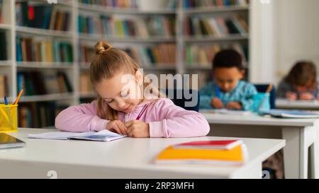 I bambini della scuola sono seduti alle scrivanie nell'interno della classe, studiano nella scuola elementare, spazio libero Foto Stock