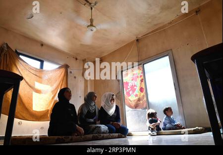 (181013) -- DAMASCO, 13 ottobre 2018 -- foto scattata l'8 ottobre 2018 mostra la 50enne Samar Sbeini (1st L) che guarda la TV con i suoi familiari e vicini nella sua casa nella città di Kafr Batna nella campagna orientale di Ghouta a Damasco, in Siria. La popolazione di Kafr Batna e di altre zone della Ghouta orientale era rimasta per anni senza elettricità fino a quando l'esercito siriano ha liberato la regione dai ribelli lo scorso maggio. Il governo siriano ha iniziato a compiere sforzi per riabilitare le aree. Ora il 70% dell'elettricità è tornato nelle aree popolate di Ghouta orientale, secondo un'elettricità Foto Stock