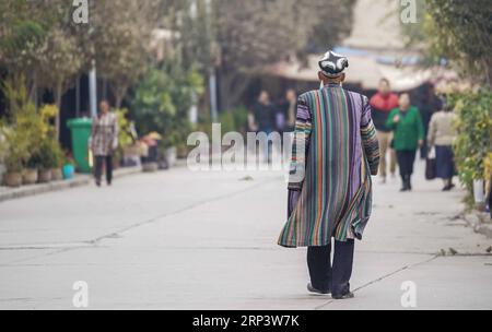 (181017) -- KASHGAR, 17 ottobre 2018 (Xinhua) -- un uomo anziano vestito in costume tradizionale cammina in una strada nella città di Kashgar, regione autonoma di Xinjiang Uygur della Cina nord-occidentale, 16 ottobre 2018. L'antica città oasi di Kashgar, nella parte più occidentale della Cina, vicino al confine con Kirghizistan, Tagikistan, Afghanistan e Pakistan, era un importante posto di sosta sulla via della seta originale ed è stata rivitalizzata come un vivace centro di affari e culture diverse. (Xinhua/Hu Huhu) (sxk) CHINA-XINJIANG-KASHGAR-DAILY LIFE (CN) PUBLICATIONxNOTxINxCHN Foto Stock