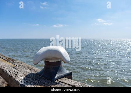 Ormeggio in palude blu con piano triangolare bianco su sfondo di legno. Ancoraggio su tavola di legno sopra il mare blu scintillante, giornata soleggiata, spazio. Foto Stock