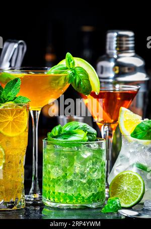 Cocktail alcolici con gin, whisky, vermouth e liquori, sfondo nero bar, atmosfera notturna Foto Stock