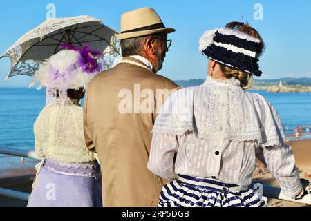 Due donne e un uomo vestiti in stile vittoriano per l'evento annuale Banos de Ola Pquio Sardinero Santander Cantabria Spagna Foto Stock