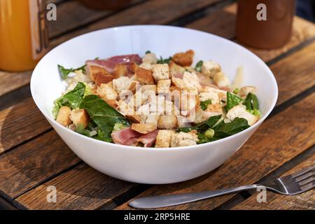 Insalata Caesar con lattuga, crostini, pancetta e pollo in un recipiente bianco Foto Stock