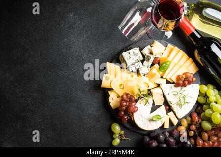 Piatto di formaggi e vino rosso su fondo nero. Foto Stock