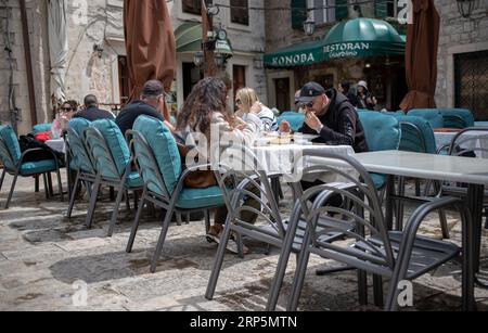 Kotor, Montenegro, 17 aprile 2023: Una taverna all'aperto con gli ospiti che cenano presso la Boka Navy Square (Trg Bokeljske Mornarice) nella città vecchia Foto Stock