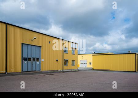 Gothenburg, Svezia - 03 giugno 2022: Parcheggio all'esterno di diversi magazzini industriali gialli e officine Foto Stock