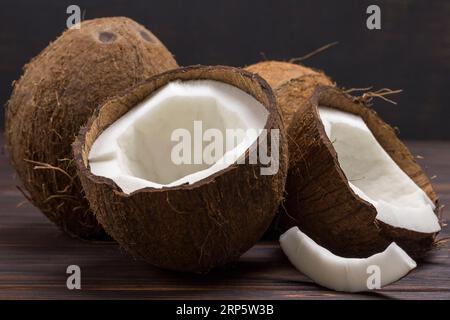 Cocco, tagliato a metà cocco su fondo di legno scuro. Cibo vegetariano nutriente. Copia spazio Foto Stock