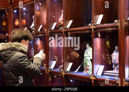 (181229) -- PECHINO, 29 dicembre 2018 (Xinhua) -- Un cliente guarda le statuette in Clay Figure Zhang Art Gallery a Tianjin, Cina settentrionale, 28 dicembre 2018. Clay Figure Zhang è un nome familiare dell'arte popolare tradizionale in Cina, e tali opere d'arte hanno una storia di quasi 200 anni. Zhang Yu, il creatore di figurine di argilla di sesta generazione della sua famiglia, si occupò dell'azienda di famiglia nel 1996, quando aveva solo 18 anni. Con il passare del tempo, l'artigianato e il marchio si sono evoluti. Invece di fare figurine e venderle come un venditore di strada, ha assunto direttori d'arte per sfruttare e commercializzare la val d'arte Foto Stock