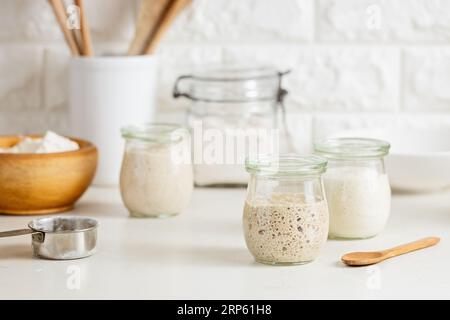 Vasetti di vetro con pasta madre attiva sul tavolo. Foto Stock