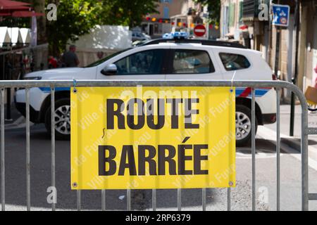 Francia, Fuveau, 3 settembre 2023, Un cartello di chiusura della strada "fermé" in francese è stato esposto in modo prominente su una barricata metallica, con un'auto della polizia sullo sfondo. Foto Stock