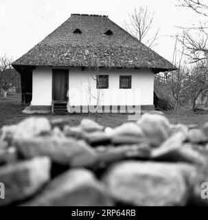 Semplice vecchia casa tradizionale con tetto di ciottoli in legno in Romania, circa 1976 Foto Stock