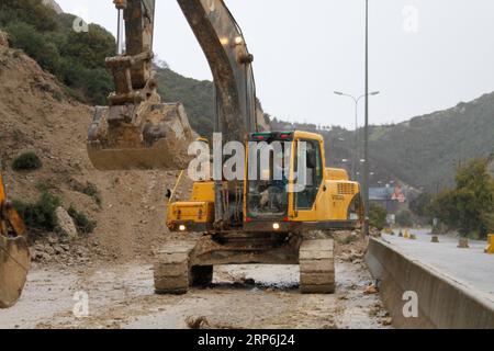 (190114) -- BEIRUT, 14 gennaio 2019 -- Un operaio guida un escavatore per sgombrare una strada tagliata da una frana sull'autostrada dalla città settentrionale di Batroun a Chekka in Libano, 14 gennaio 2019. La frana è stata causata da forti piogge durante la notte. ) LEBANON-BATROUN-LANDSLIDE Khalid PUBLICATIONxNOTxINxCHN Foto Stock