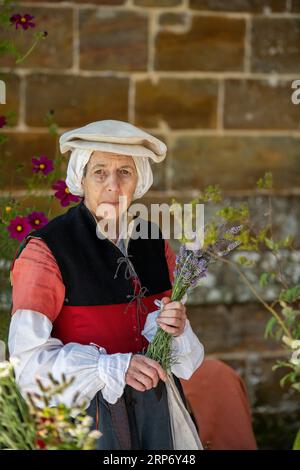 signora anziana vestita con costume da donna tudor o vestito in una fiera di rievocazione sull'isola di wight. Foto Stock