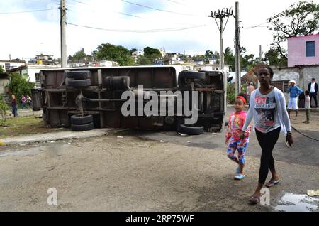 (190129) -- L'AVANA, 29 gennaio 2019 (Xinhua) -- le persone camminano davanti a un camion rovesciato nella zona colpita da tornado nel comune di Regla a l'Avana, Cuba, 28 gennaio 2019. Un potente tornado attraversò la capitale cubana domenica notte, lasciando tre persone morte e 172 feriti. (Xinhua/Joaquin Hernandez) CUBA-HAVANA-TORNADO PUBLICATIONxNOTxINxCHN Foto Stock