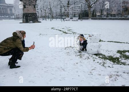 (190130) -- BRUXELLES, 30 gennaio 2019 (Xinhua) -- Un bambino posa per foto con un pupazzo di neve nel Parco del cinquantesimo anniversario a Bruxelles, Belgio, 30 gennaio 2019. Una nevicata ha colpito Bruxelles mercoledì. (Xinhua/Zhang Cheng) BELGIO-BRUXELLES-NEVICATE PUBLICATIONxNOTxINxCHN Foto Stock