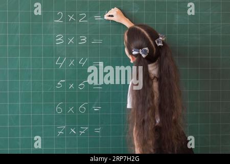 Ragazza che fa calcoli su una lavagna Foto Stock