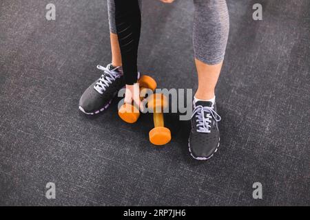 Vista parziale bassa per donna che sceglie una palestra con manubri Foto Stock