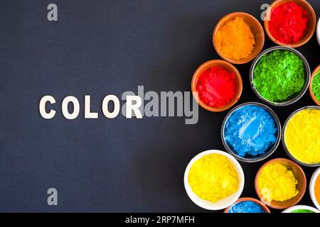 Testo a colori con diversi tipi di colore holi polvere ciotola sfondo nero Foto Stock