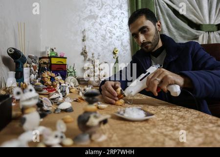 (190213) -- GAZA, 13 febbraio 2019 -- il giovane palestinese Ahmed al-Madhoun, 31 anni, realizza un'opera d'arte con conchiglie nella sua casa a Gaza, il 10 febbraio 2019. Un giovane palestinese di Gaza trasforma conchiglie in splendidi manufatti che adornano la sua casa per soddisfare la sua passione per questo tipo di arte. Utilizzando conchiglie che raccoglie dalle spiagge di Gaza, Ahmed al-Madhoun, 31 anni, realizza varie opere d'arte come animali, uccelli e alcuni personaggi divertenti. Al-Madhoun, che ha conseguito una laurea in ingegneria radiotelevisiva e lavora per una compagnia di telecomunicazioni locale, ha collezionato multipli Foto Stock