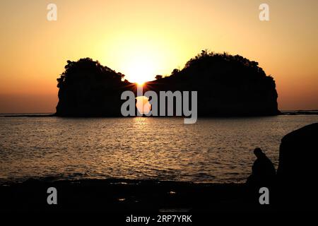 (190213) -- PECHINO, 14 febbraio 2019 (Xinhua) -- foto scattata il 13 febbraio 2019 mostra Engetsu Island al tramonto a Wakayama, Giappone. Engetsu Island è una piccola isola con un arco naturale al largo della costa di Shirahama, nella prefettura di Wakayama in Giappone. (Xinhua/Du Xiaoyi) XINHUA FOTO DEL GIORNO PUBLICATIONxNOTxINxCHN Foto Stock