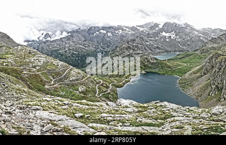 Foto con saturazione a gamma dinamica ridotta HDR di vista delle serpentine con tornanti dal Colle del Nivolet, passo Nivolet, davanti al Lago Agnel Foto Stock