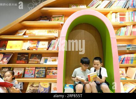 (190218) -- PECHINO, 18 febbraio 2019 -- Du Zihao (1st R), un bibliotecario volontario, introduce un libro a un bambino nella libreria Jimo di Qingdao City, nella provincia dello Shandong della Cina orientale, 19 luglio 2018. I lettori cinesi, molti dei quali erano passati ai dispositivi di lettura elettronica e alle librerie online, stanno tornando ai negozi tradizionali, offrendo una gamma più ampia di nuovi prodotti. Il Bookdao New Publishing Institute, una società di consulenza per l'industria editoriale e di vendita di libri del paese, ha intervistato 62 catene e ha scoperto che circa il 65% prevede di aprire più di cinque nuovi negozi quest'anno, e il 18% Foto Stock