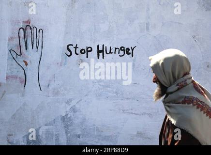 News Themen der Woche KW08 News Bilder des Tages 190221 - SANAA, 21 febbraio 2019 - Un anziano yemenita cammina per graffiti mostrando Stop Hunger su un muro a Sanaa, Yemen, 21 febbraio 2019. Una campagna di graffiti di artisti yemeniti è stata messa in scena per richiamare l'attenzione del mondo sullo Yemen e sulle persone che soffrono la fame a causa di più di quattro anni di guerra. Mohammed Mohammed YEMEN-SANAA-GRAFFITI-ANTI-FAME nieyunpeng PUBLICATIONxNOTxINxCHN Foto Stock