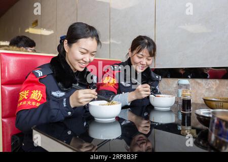 (190225) -- SHIJIAZHUANG, 25 febbraio 2019 -- Zhang Zi (R) e Wang lei mangiano spaghetti durante una pausa pranzo, a Shijiazhuang, nella provincia di Hebei nella Cina settentrionale, il 23 febbraio 2019. Durante la corsa di quest'anno al Festival di Primavera, Zhang Zi, un ufficiale di polizia ferroviaria di 32 anni, ha lavorato insieme al suo apprendista Wang lei, un ufficiale di 24 anni. Sono stati impegnati ad aiutare i passeggeri, a gestire le emergenze e a mantenere l'ordine alla stazione ferroviaria di Shijiazhuang. Questa è la seconda volta che la coppia lavora insieme durante la corsa di viaggio del Festival di Primavera. ) CHINA-SHIJIAZHUANG-POLICE-APPRENTICE (CN) MUXYU Foto Stock