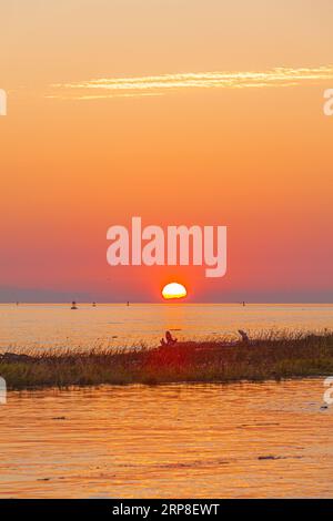 Il sole tramonta sull'isola di Vancouver visto da Steveston, nella Columbia Britannica, Canada Foto Stock