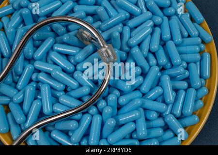 Piastra gialla piena di capsule medicinali blu che rappresentano il sovradosaggio del farmaco. vista dall'alto Foto Stock