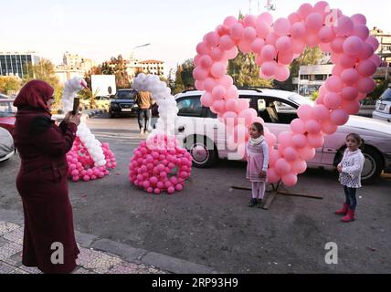 (190322) -- DAMASCO, 22 marzo 2019 -- Una donna scatta foto di suo figlio davanti a palloncini a forma di cuore in occasione della festa della mamma siriana a Damasco, in Siria, il 21 marzo 2019. ) SIRIA-DAMASCO-FESTA DELLA MAMMA AmmarxSafarjalani PUBLICATIONxNOTxINxCHN Foto Stock