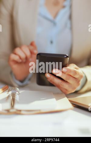 Primo piano su una contabile che lavora in un ufficio ecologico con smartphone e notebook. Foto Stock