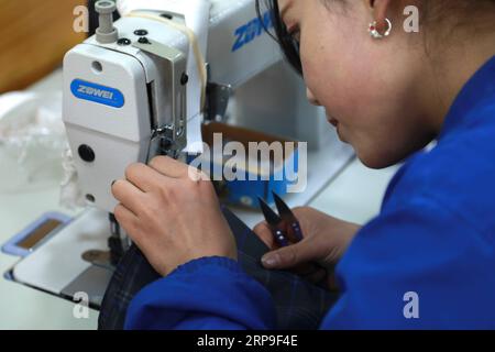 (190405) -- DONGXIANG, 5 aprile 2019 (Xinhua) -- Un lavoratore lavora un tessuto ombrello con una macchina da cucire in un laboratorio nella contea autonoma di Dongxiang, provincia del Gansu della Cina nordoccidentale, 3 aprile 2019. Dal 2018, ai laboratori di riduzione della povertà è stata data la priorità nell'accelerare la campagna di aiuto alla povertà in corso nella contea autonoma di Dongxiang, con la quale le persone colpite dalla povertà si sono guadagnate un lavoro costante per aiutare a uscire dalla povertà. Finora, sono stati istituiti 18 workshop per la riduzione della povertà, creando opportunità di lavoro per oltre 700 persone del posto, tra cui più di 500 imp registrati Foto Stock