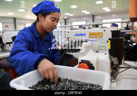 (190405) -- DONGXIANG, 5 aprile 2019 (Xinhua) -- Un lavoratore lavora un tessuto ombrello con una macchina da cucire in un laboratorio nella contea autonoma di Dongxiang, provincia del Gansu della Cina nordoccidentale, 3 aprile 2019. Dal 2018, ai laboratori di riduzione della povertà è stata data la priorità nell'accelerare la campagna di aiuto alla povertà in corso nella contea autonoma di Dongxiang, con la quale le persone colpite dalla povertà si sono guadagnate un lavoro costante per aiutare a uscire dalla povertà. Finora, sono stati istituiti 18 workshop per la riduzione della povertà, creando opportunità di lavoro per oltre 700 persone del posto, tra cui più di 500 imp registrati Foto Stock