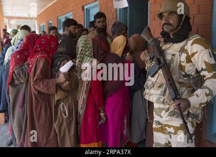 (190423) -- SRINAGAR, 23 aprile 2019 (Xinhua) -- un gruppo paramilitare indiano è in guardia mentre gli elettori si mettono in fila per lanciare le loro schede elettorali in un centro di votazione nel villaggio di Chaklipora, nel distretto di Anantnag, circa 85 km a sud di Srinagar, la capitale estiva del Kashmir controllato dagli indiani, 23 aprile 2019. Il voto è iniziato martedì nel distretto di Anantnag del Kashmir controllato dagli indiani durante la terza fase delle 17 elezioni generali in India. (Xinhua/Javed Dar) KASHMIR-SRINAGAR-ELEZIONI GENERALI INDIANE PUBLICATIONxNOTxINxCHN Foto Stock