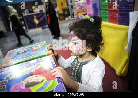 (190428) -- TEHERAN, 28 aprile 2019 -- A child views a book at the 32nd Teheran International Book Fair in Teheran, Iran, 27 aprile 2019. Durante la fiera del libro di 11 giorni, che termina il 4 maggio, circa 2.400 editori iraniani mostrano 300.000 titoli di libri, mentre circa 800 editori stranieri mostrano 137.000 le loro ultime pubblicazioni. ) IRAN-TEHERAN-FIERA INTERNAZIONALE DEL LIBRO AhmadxHalabisaz PUBLICATIONxNOTxINxCHN Foto Stock