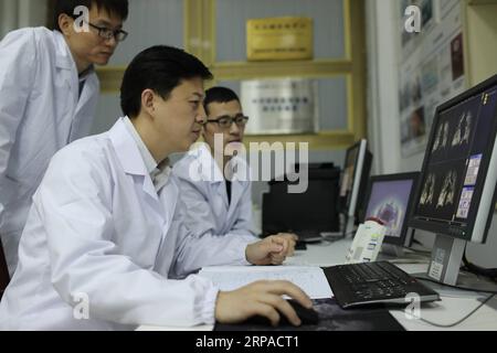 (190504) - WUHAN, 4 maggio 2019 (Xinhua) - Zhou Xin (C) discute con i suoi colleghi sulla qualità delle immagini di risonanza magnetica polmonare umana presso l'Istituto di fisica e matematica di Wuhan dell'Accademia cinese delle scienze di Wuhan, capitale della provincia di Hubei della Cina centrale, 18 aprile 2019. Il professor Zhou Xin è il vice direttore dell'Istituto di fisica e matematica di Wuhan dell'Accademia Cinese delle Scienze, del laboratorio di Stato chiave di risonanza magnetica e fisica atomica e molecolare e del Centro Nazionale per la risonanza magnetica di Wuhan. È interessato alle immagini a risonanza magnetica ultrasensibile Foto Stock