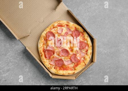 Vista dall'alto della pizza con salsiccia e prosciutto di maiale in scatola di cartone Foto Stock