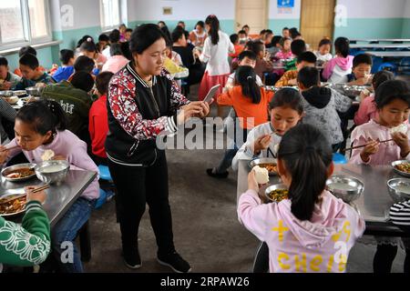 (190519) -- WANRONG, 19 maggio 2019 (Xinhua) -- l'insegnante Sun Yinli scatta foto di alunni che pranzano alla Dingfan Primary School a Gaocun Township della contea di Wanrong, nella provincia dello Shanxi della Cina settentrionale, 15 maggio 2019. La maggior parte dei 110 alunni della Dingfan Primary School sono bambini lasciati indietro, i cui genitori sono diventati lavoratori migranti in città. Alcuni studenti provenivano da famiglie povere registrate a Dingfan e nei villaggi vicini. Nel settembre del 2015, il maestro Zhao Yingjie ha chiesto di aggiungere la scuola all'elenco del pranzo libero per bambini (FLC), l'iniziativa pubblica di offrire pasti gratuiti Foto Stock