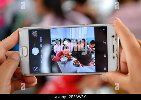 (190519) -- WANRONG, 19 maggio 2019 (Xinhua) -- Un insegnante della Dingfan Primary School scatta foto degli alunni che pranzano alla Dingfan Primary School a Gaocun Township della contea di Wanrong, nella provincia dello Shanxi della Cina settentrionale, 15 maggio 2019. La maggior parte dei 110 alunni della Dingfan Primary School sono bambini lasciati indietro, i cui genitori sono diventati lavoratori migranti in città. Alcuni studenti provenivano da famiglie povere registrate a Dingfan e nei villaggi vicini. Nel settembre del 2015, il maestro Zhao Yingjie ha chiesto di aggiungere la scuola all'elenco del pranzo libero per bambini (FLC), l'iniziativa pubblica Foto Stock