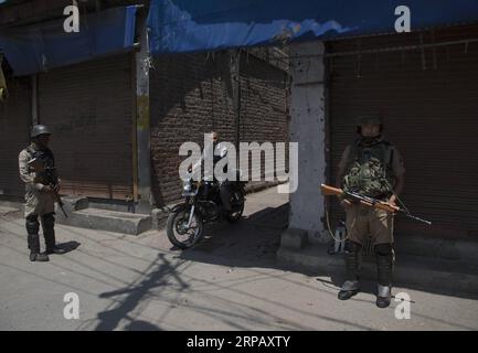 (190521) -- SRINAGAR, 21 maggio 2019 (Xinhua) -- le truppe paramilitari indiane stanno di guardia mentre un uomo cavalca la sua bicicletta durante il blocco di sicurezza nel centro di Srinagar, la capitale estiva del Kashmir controllato dagli indiani, 21 maggio 2019. Le autorità di lunedì hanno imposto restrizioni in alcune parti di Srinagar per prevenire le proteste come i gruppi separatisti hanno chiesto uno sciopero e una marcia commemorativa per celebrare l'anniversario della morte di due leader separatisti, Mirwaiz Muhammad Farooq e Abdul Gani Lone, hanno detto funzionari. (Xinhua/Javed Dar) KASHMIR-SRINAGAR-SECURITY-LOCKDOWN PUBLICATIONxNOTxINxCHN Foto Stock