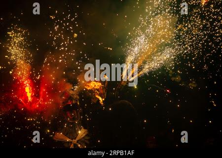 Drago che emerge dal fumo con la bocca aperta e che fuoriesce dalla lingua illuminato da fuochi d'artificio e fuoco che fuoriesce dalle ali durante il Co Foto Stock