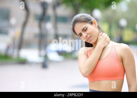 Donna sportiva che soffre di mal di collo lamentandosi di stare in strada Foto Stock