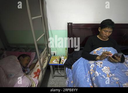 (190601) -- PECHINO, 1 giugno 2019 (Xinhua) -- Wang Beihai (R) chiacchiera con la sua famiglia via cellulare dopo che Chen Weiyu si è addormentato nella loro camera da letto della scuola elementare di Sanhe nella città di Ruijin, nella provincia del Jiangxi della Cina orientale, 7 maggio 2019. La scuola elementare di Sanhe, situata nelle montagne di Ruijin, ha un solo insegnante, Wang Beihai di 46 anni, e uno studente Chen Weiyu, un ragazzo di 9 anni di una famiglia povera. Lo studente Chen Weiyu, che viveva con sua nonna, era solito studiare in una scuola a circa 20 chilometri da casa sua. Suo nonno l'ha dovuto portare da lui Foto Stock