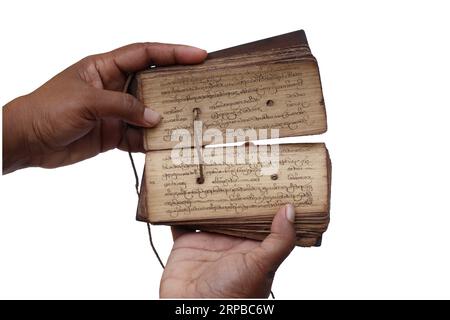 La postura di tenere in mano un antico manoscritto di foglie di palma e tenere aperto il libro e rivelare il contenuto all'interno. Foto Stock